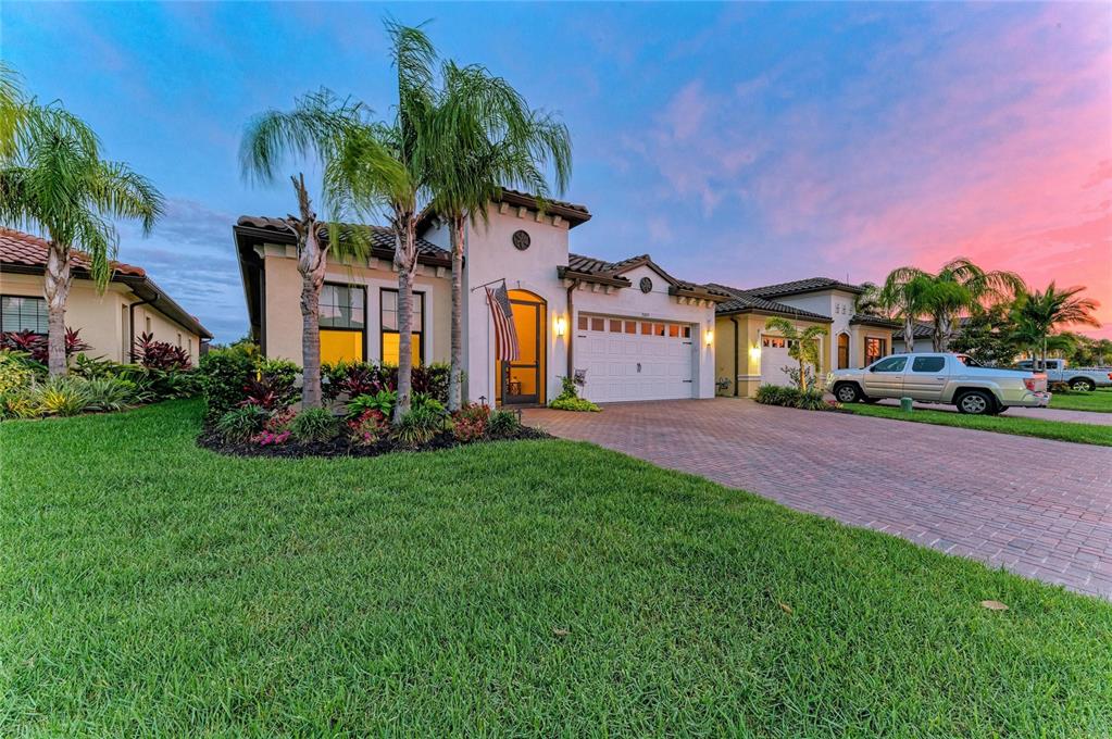 A single-story stucco house with a brick paver driveway and palm trees at sunset — 2005 6TH ST E, PALMETTO, FL