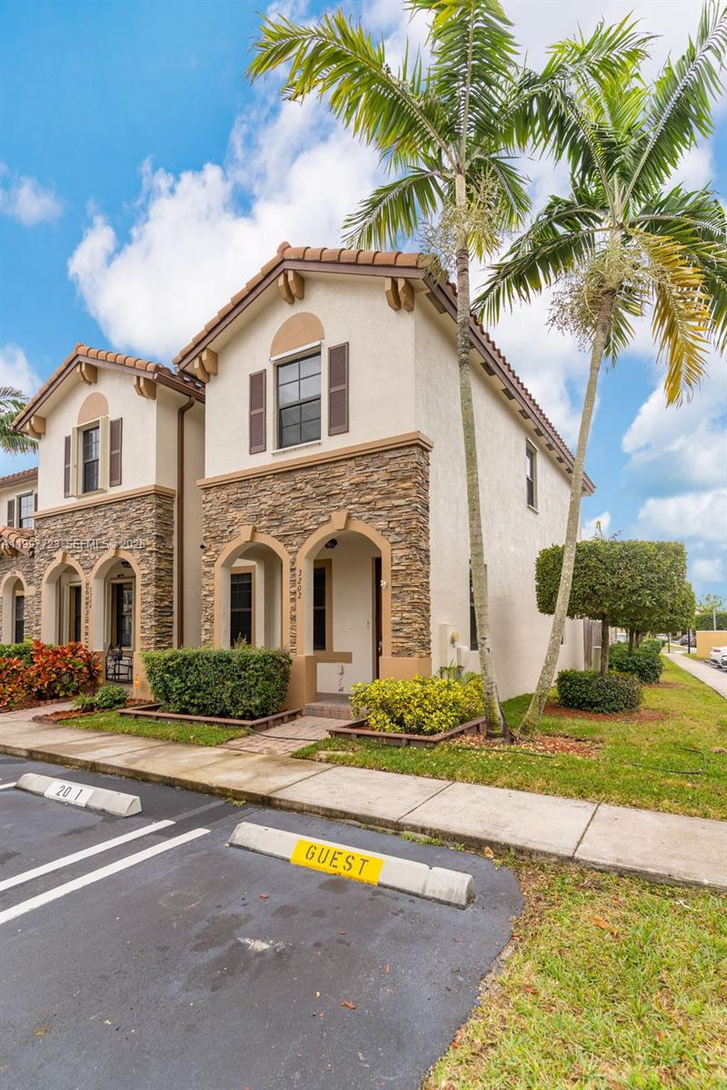 A two-story stucco townhouse with stone veneer accents and a palm tree in the front — 3202 SE 6th St, Homestead FL 33033, HOMESTEAD, FL
