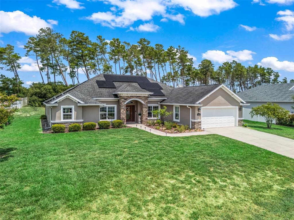A single-story house with a stone-accented entryway, solar panels on the roof, and a lawn — 4443 SW 108TH PLACE, OCALA, FL