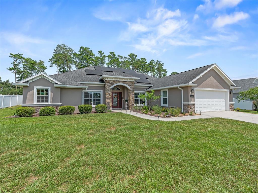 A single-story house with a stone-accented entryway, solar panels, and an attached two-car garage — 4443 SW 108TH PLACE, OCALA, FL