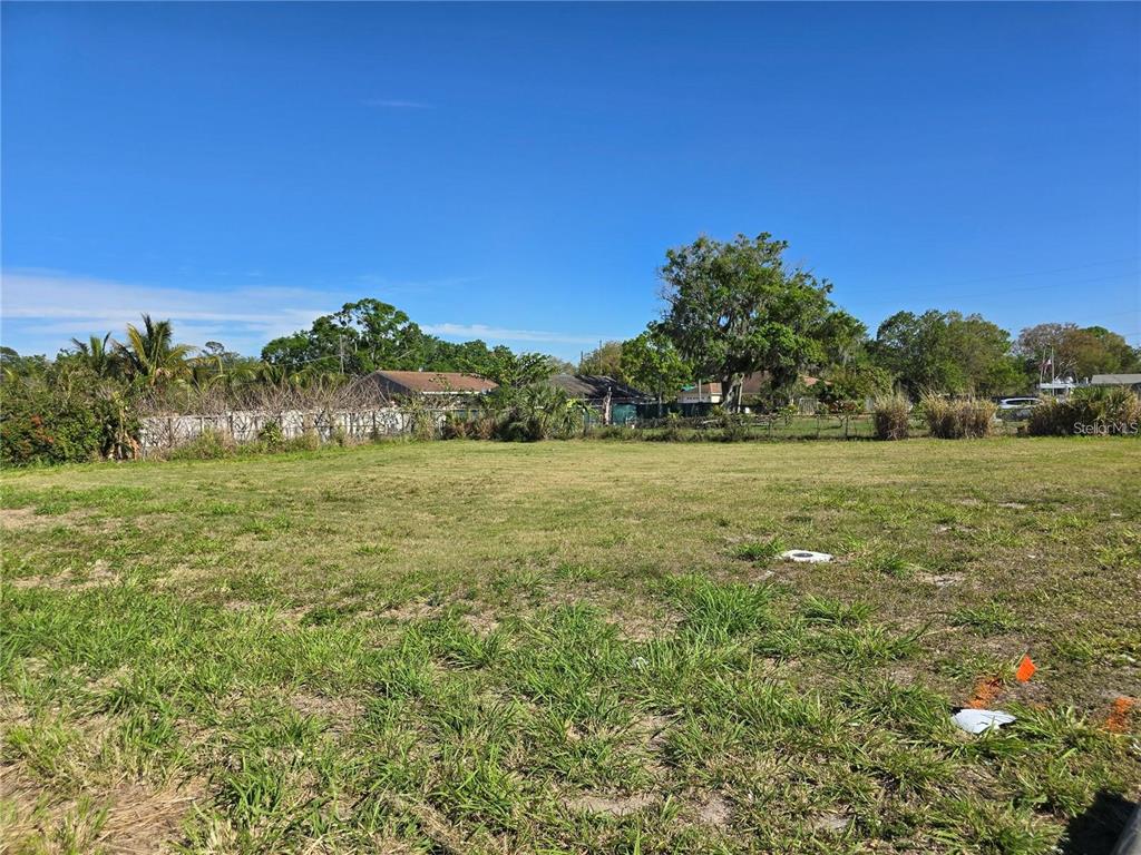 A flat, grassy vacant lot with trees and a fence in the background — 205 SNIVELY AVENUE, ELOISE, FL