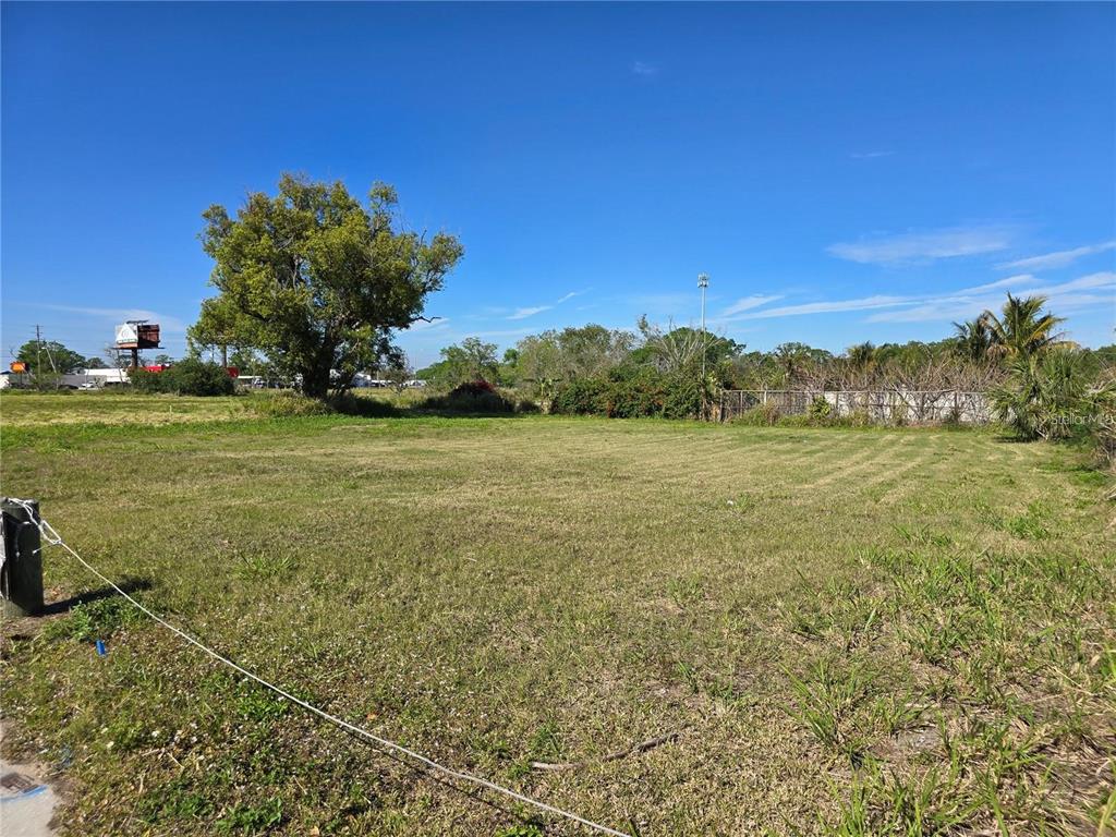 A flat, grassy vacant lot features a large tree and a distant fence line — 205 SNIVELY AVENUE, ELOISE, FL