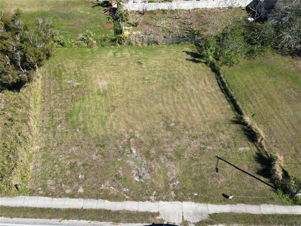 An aerial view of a rectangular, vacant grassy lot bordered by a sidewalk and trees — 205 SNIVELY AVENUE, ELOISE, FL