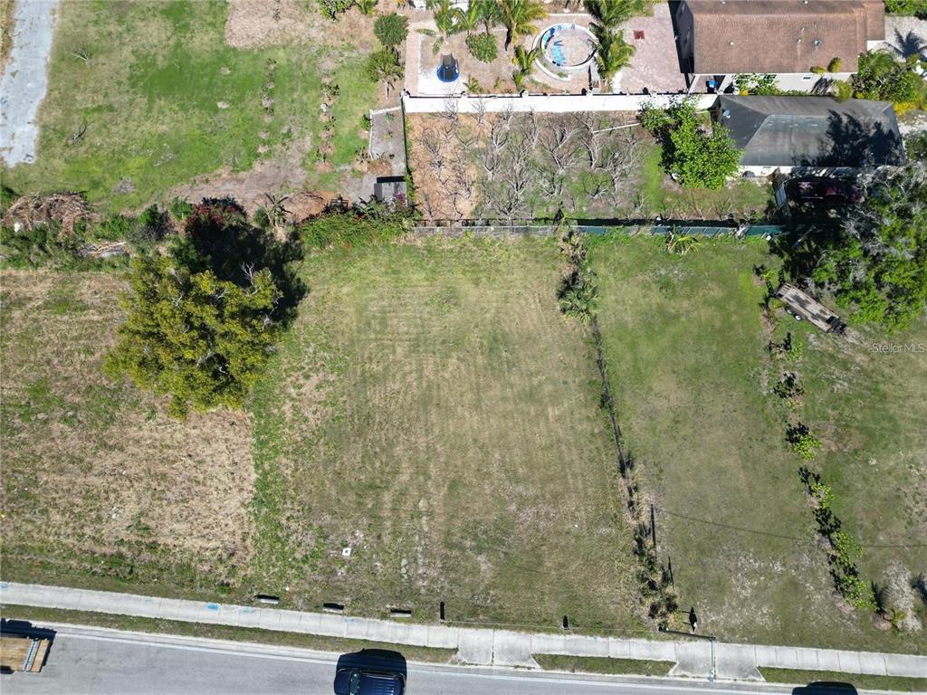 An aerial view shows a vacant, grassy residential lot bordered by a road and trees — 205 SNIVELY AVENUE, ELOISE, FL