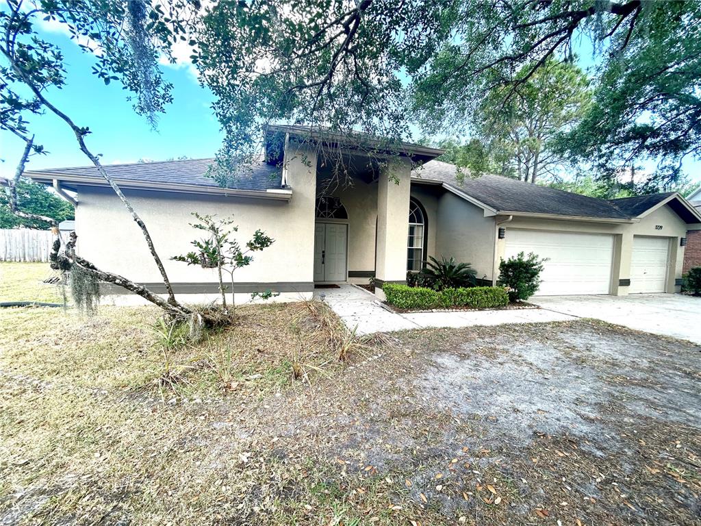 A single-story house with a beige stucco exterior, a two-car garage, and a covered entryway — 1729 BUCKHORN PLACE, ORLANDO, FL