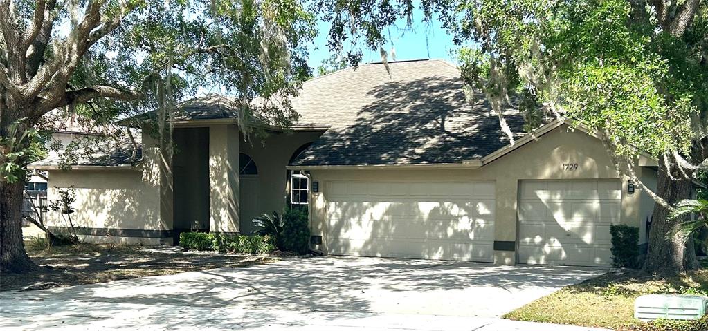 A single-story house with a beige stucco exterior, a shingled roof, and a three-car garage — 1729 BUCKHORN PLACE, ORLANDO, FL