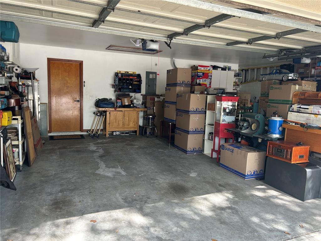 A cluttered garage with a wooden door, concrete floor, and numerous stacked cardboard boxes — 1729 BUCKHORN PLACE, ORLANDO, FL