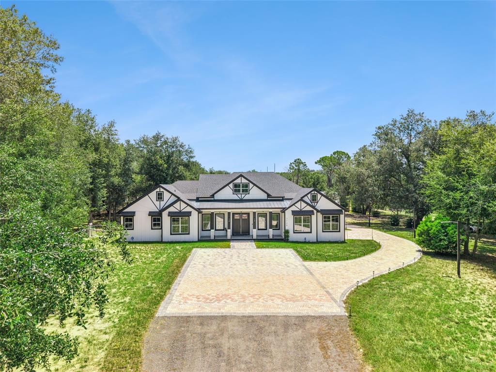 A white, single-story house with a dark roof and a paved driveway sits among trees — 7739 N CHERRY LAKE GROVES ROAD, GROVELAND, FL
