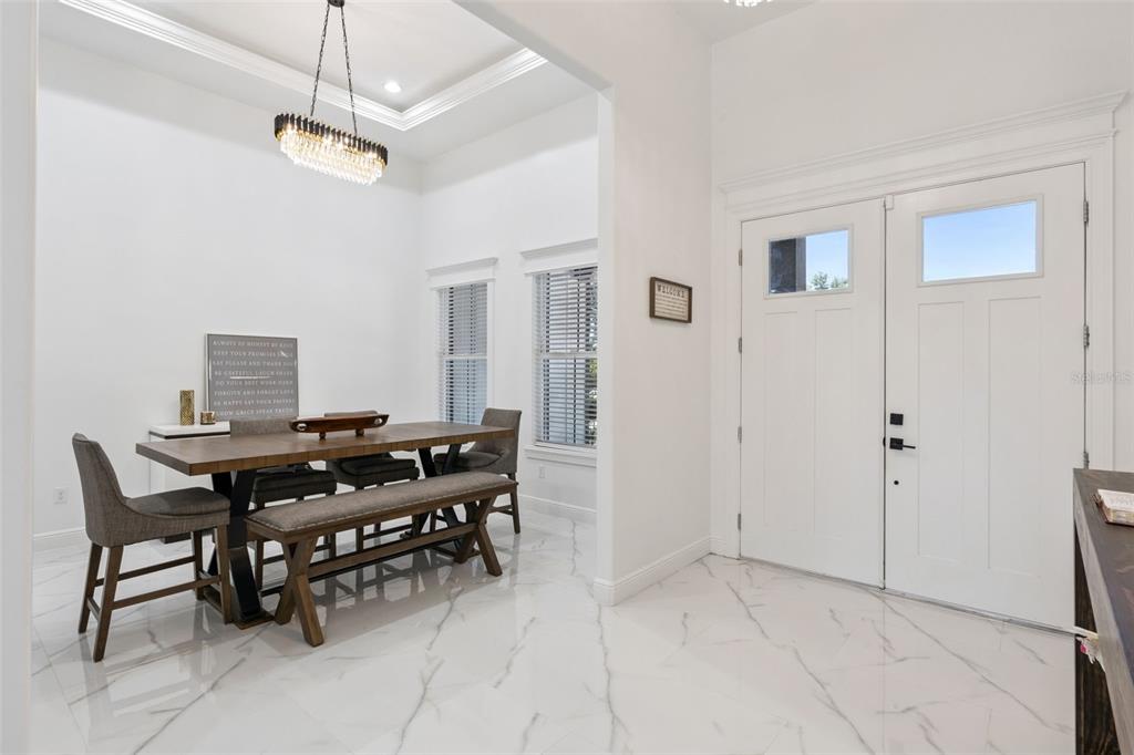 A dining area with a wooden table, bench, and chairs sits beside a white entryway door — 7739 N CHERRY LAKE GROVES ROAD, GROVELAND, FL