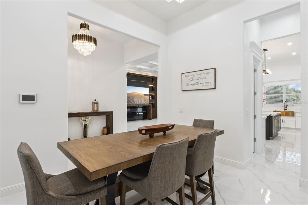 A dining room with a wooden table, gray chairs, and a chandelier, opening to a kitchen — 7739 N CHERRY LAKE GROVES ROAD, GROVELAND, FL
