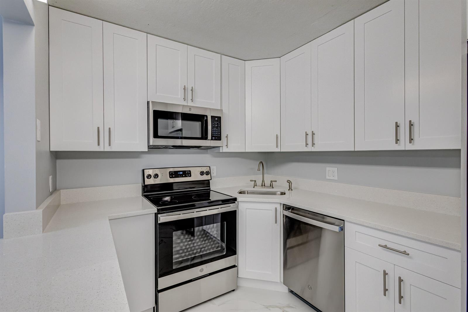 A kitchen features white shaker cabinets, stainless steel appliances, and light-colored quartz countertops — 4821 Sable Pine Circle, West Palm Beach FL 33417, WEST PALM BEACH, FL