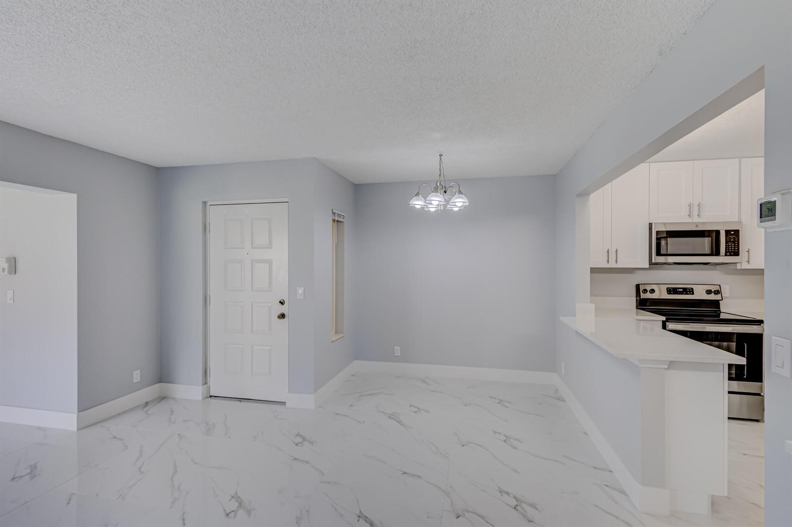 A dining area with white marble-look tile floors, light gray walls, and a chandelier — 4821 Sable Pine Circle, West Palm Beach FL 33417, WEST PALM BEACH, FL