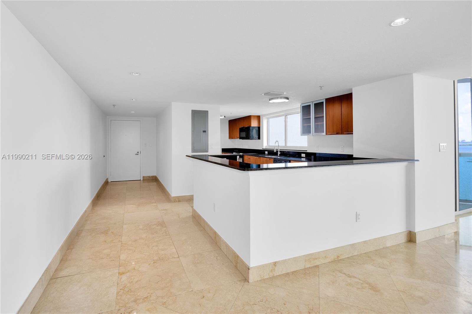 An open-concept living area features marble floors, a kitchen island, and floor-to-ceiling windows overlooking water — 1800 N Bayshore Dr # 1901, Miami FL 33132, MIAMI, FL