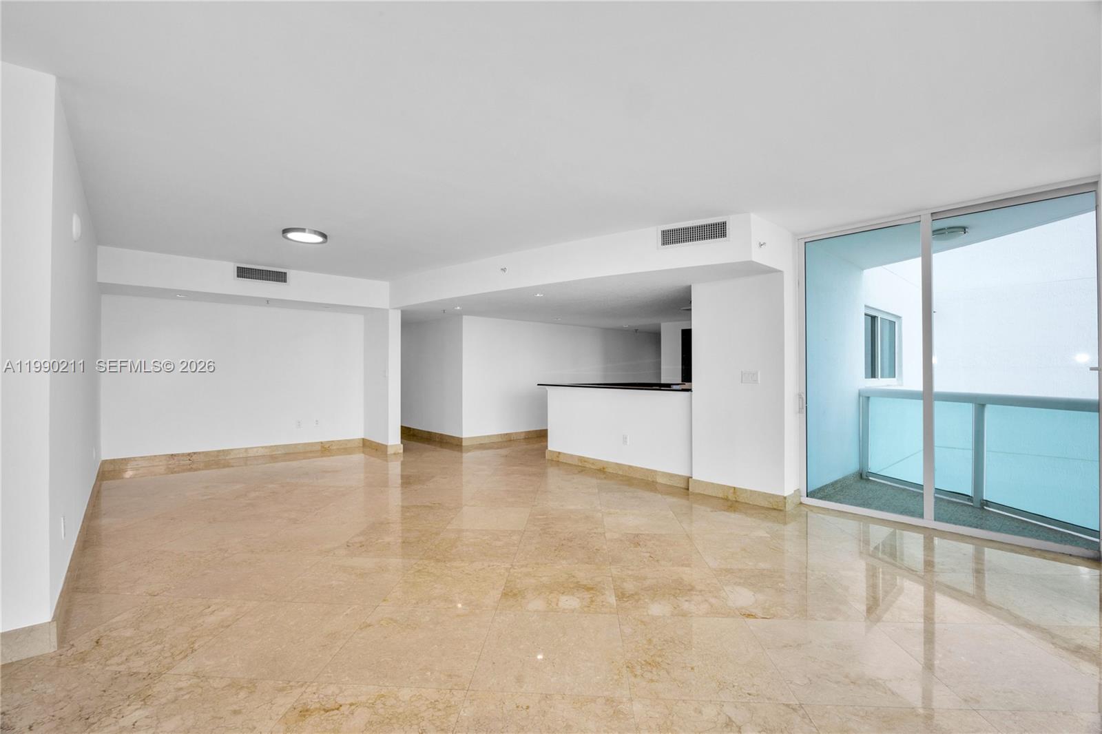 A kitchen with wood cabinets and black countertops overlooks a tiled living area — 1800 N Bayshore Dr # 1901, Miami FL 33132, MIAMI, FL