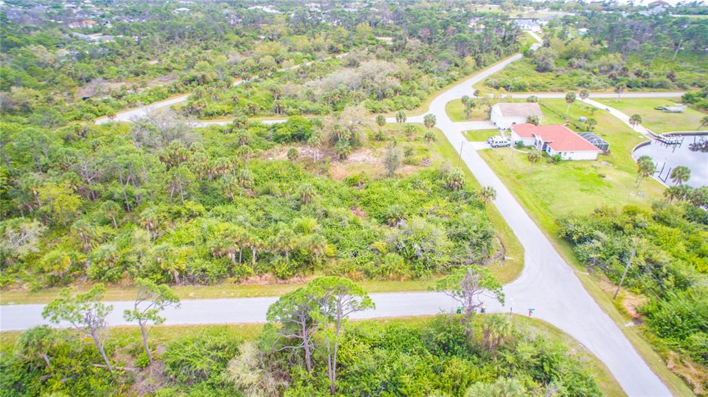 An aerial view shows a vacant, wooded residential lot situated at a road intersection — 1310 BRAKLET TERRACE, PORT CHARLOTTE, FL