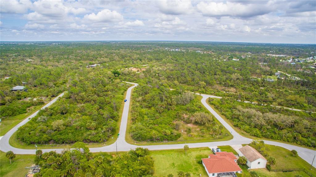 An aerial view of a residential street with undeveloped wooded lots and a nearby house — 1310 BRAKLET TERRACE, PORT CHARLOTTE, FL