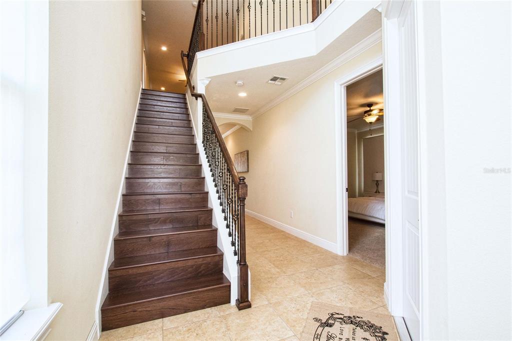 A staircase with dark wood treads and a metal railing leads to an upper landing — 7824 LOXAHATCHEE COURT, REUNION, FL