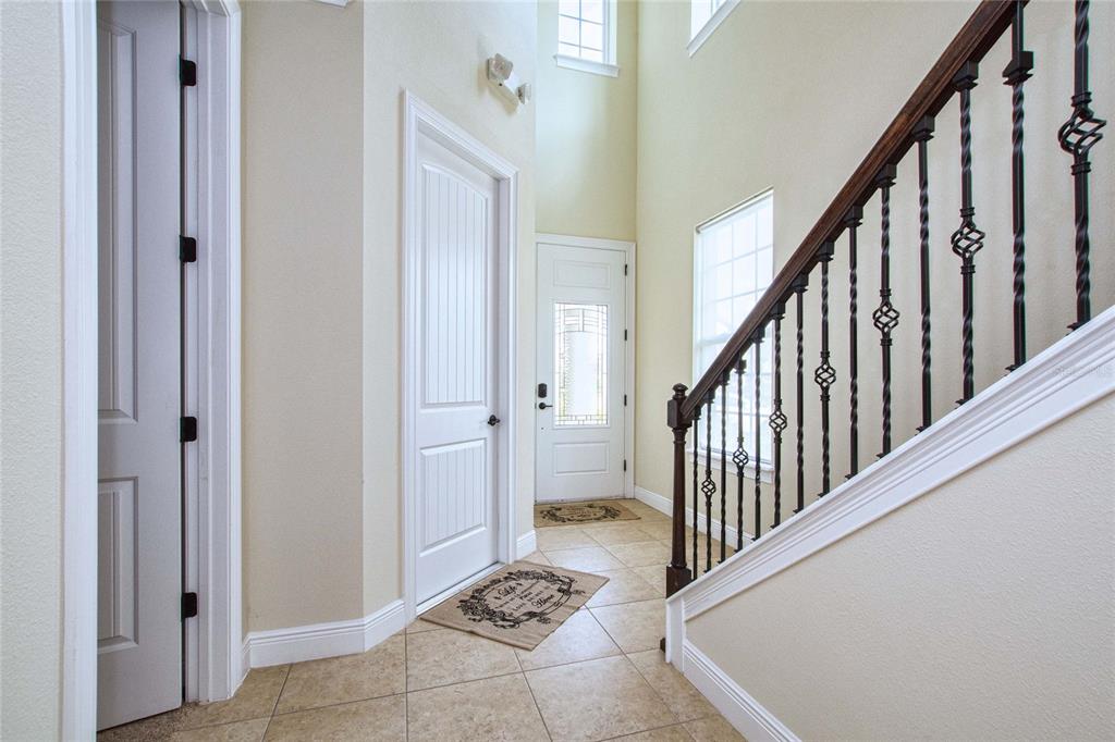 An entryway features tile flooring, a staircase with iron balusters, and two white interior doors — 7824 LOXAHATCHEE COURT, REUNION, FL
