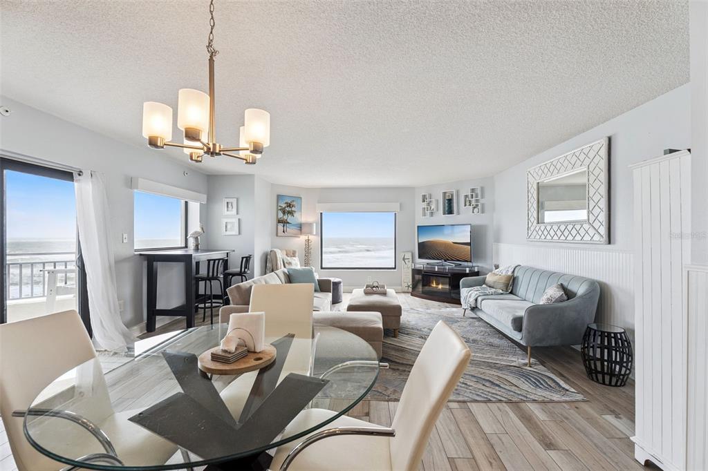 A bright living and dining area features ocean views, light wood flooring, and coastal decor — 5207 S ATLANTIC AVENUE UNIT 425, NEW SMYRNA BEACH, FL