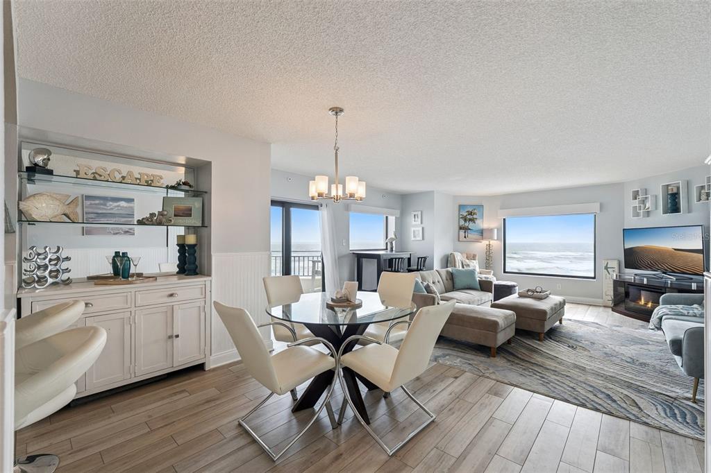 An open-concept living and dining area with ocean views, light wood floors, and modern furniture — 5207 S ATLANTIC AVENUE UNIT 425, NEW SMYRNA BEACH, FL