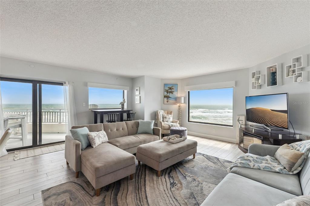 A living room with a sectional sofa, ocean views, and light-colored tile flooring — 5207 S ATLANTIC AVENUE UNIT 425, NEW SMYRNA BEACH, FL
