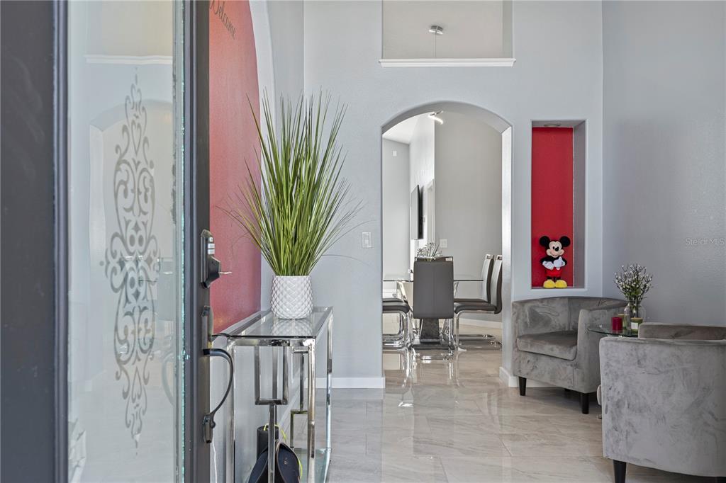 An entryway features a glass-paneled door, a chrome console table, and an arched doorway — 215 ELDERBERRY DRIVE, DAVENPORT, FL