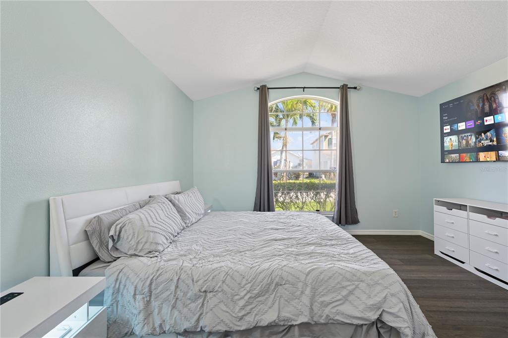 A bedroom features light blue walls, a white bed, a large window, and a wall-mounted television — 215 ELDERBERRY DRIVE, DAVENPORT, FL