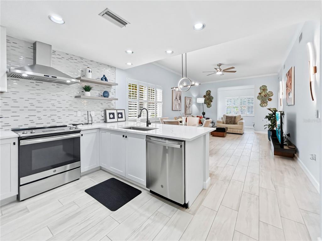A modern kitchen with white cabinets and stainless steel appliances opens into a living area — 3701 54TH DRIVE W UNIT 104, BRADENTON, FL
