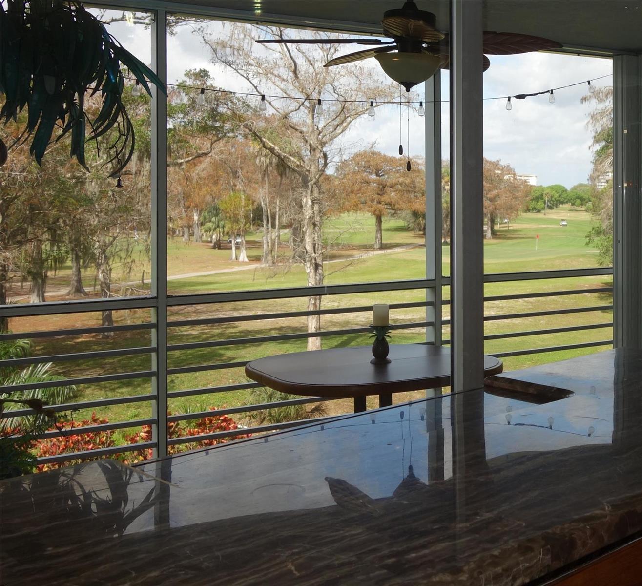 A screened-in porch with a dark stone countertop overlooks a golf course and trees — 625 Oaks Drive # 302, Pompano Beach FL 33069, POMPANO BEACH, FL