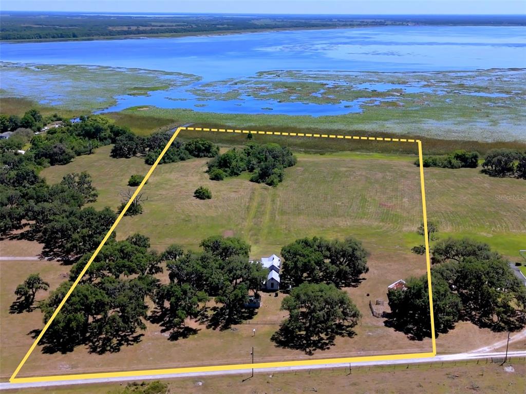 An aerial view shows a rural property with a house and trees bordering a lake — 3650 LAKE TOHOPEKALIGA ROAD, ST CLOUD, FL