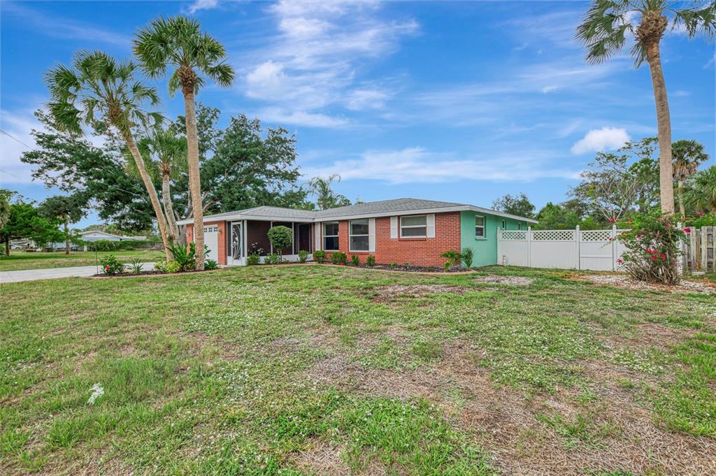 A single-story brick house with a screened porch and palm trees on a grassy lot — 1460 CORTES DRIVE, ENGLEWOOD, FL