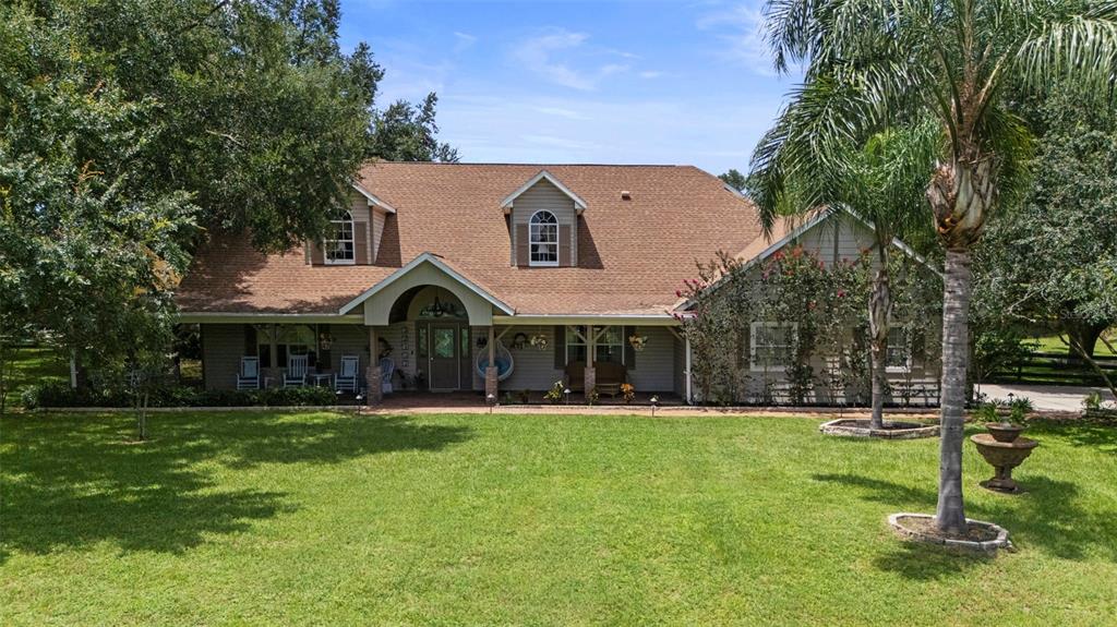 A single-story house with a covered porch, dormer windows, and a large front lawn — 32137 WOLF BRANCH LANE, SORRENTO, FL