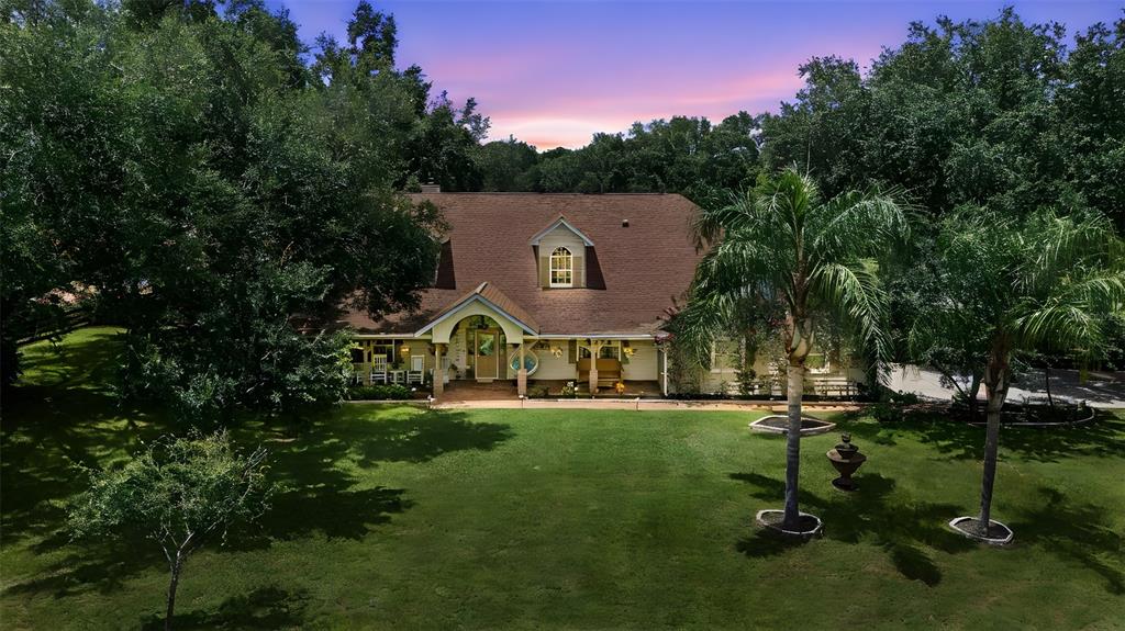 A covered front porch features a beige door with stained glass, a hanging chair, and seating — 32137 WOLF BRANCH LANE, SORRENTO, FL