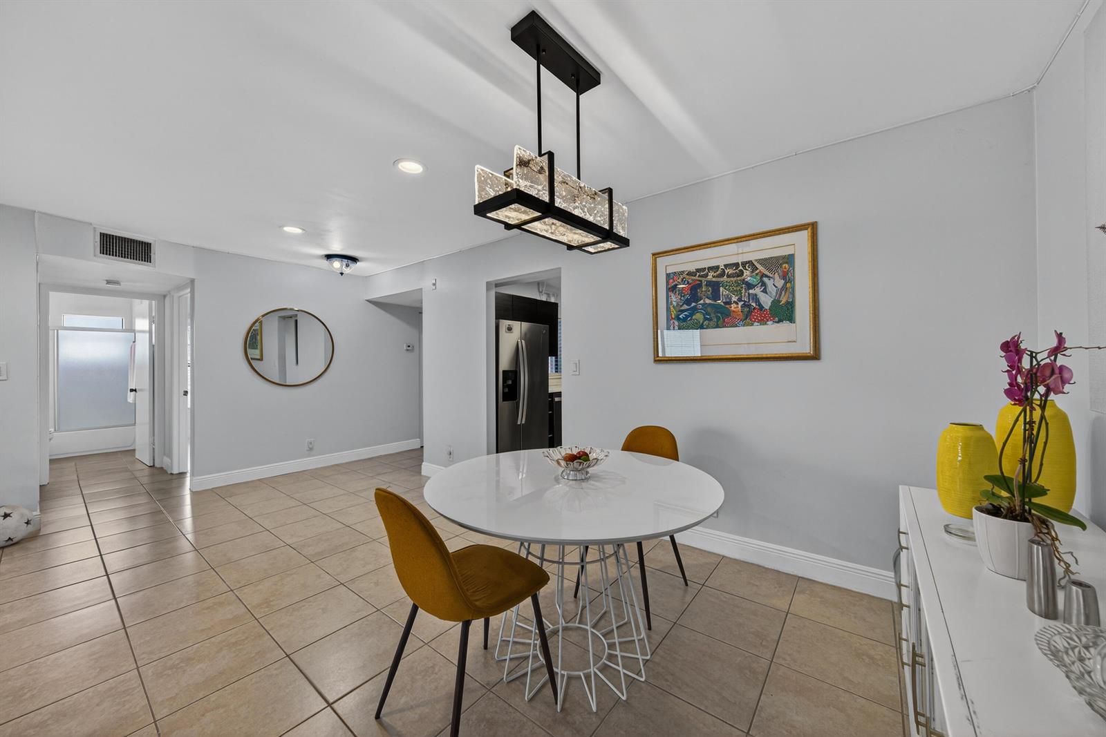 A dining area features a white round table, two mustard chairs, and a modern light fixture — 8565 W Boca Glades Blvd # C, Boca Raton FL 33434, BOCA RATON, FL