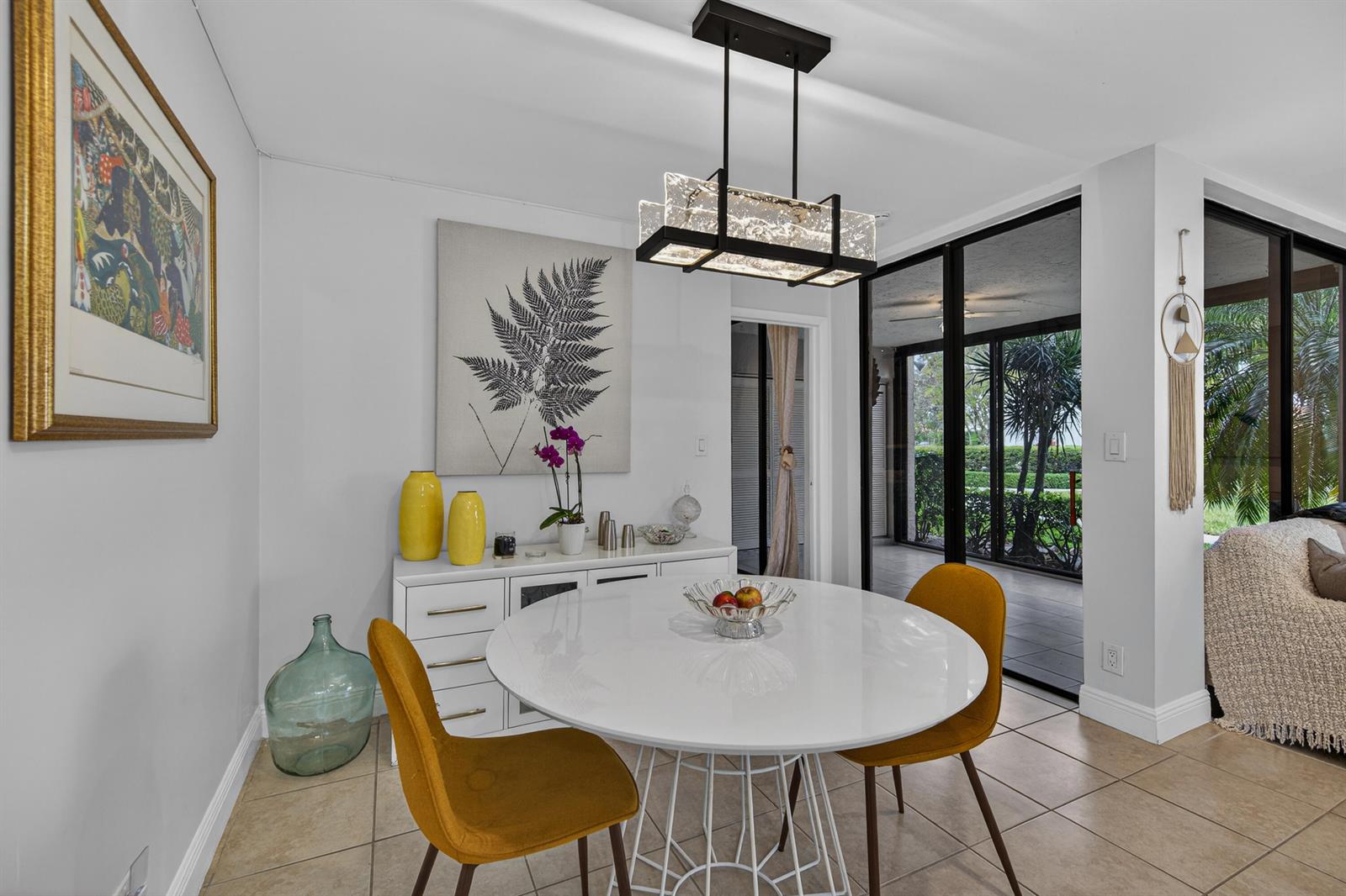 A dining area features a white round table, yellow chairs, and a modern rectangular chandelier — 8565 W Boca Glades Blvd # C, Boca Raton FL 33434, BOCA RATON, FL