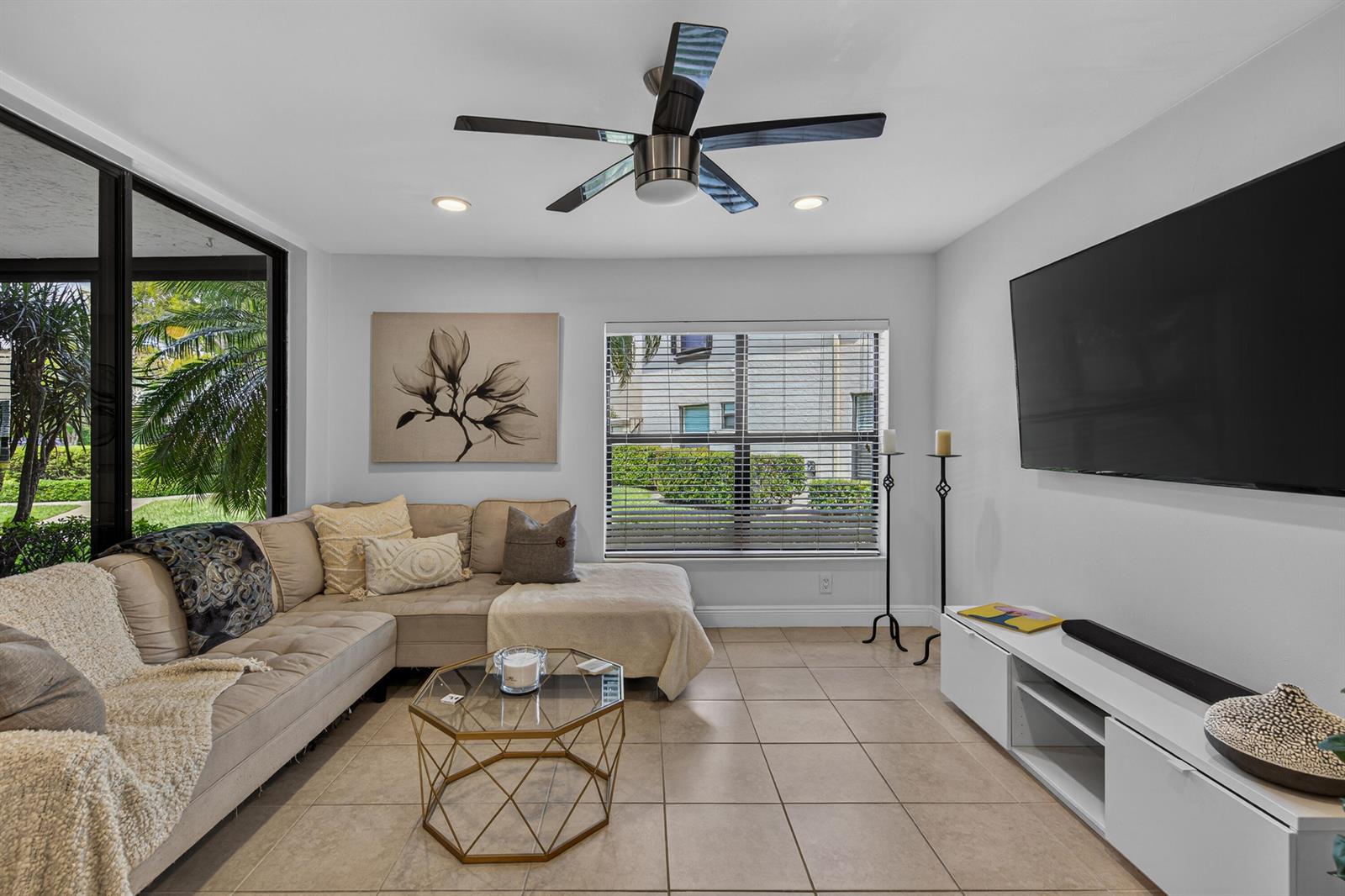 A living room features a beige sectional sofa, a glass coffee table, and a wall-mounted television — 8565 W Boca Glades Blvd # C, Boca Raton FL 33434, BOCA RATON, FL