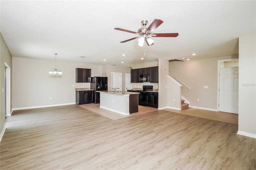 An open-concept kitchen and living area features dark wood cabinets, granite countertops, and light flooring — 16726 SECRET MEADOW DRIVE, ODESSA, FL