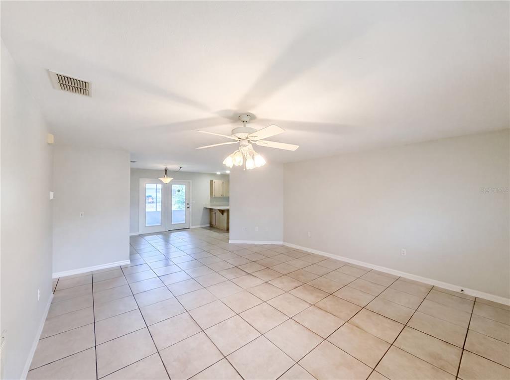 A spacious room features light-colored tile flooring, a ceiling fan, and an adjacent kitchen area — 4846 MAC DONALD STREET, LAKE WALES, FL