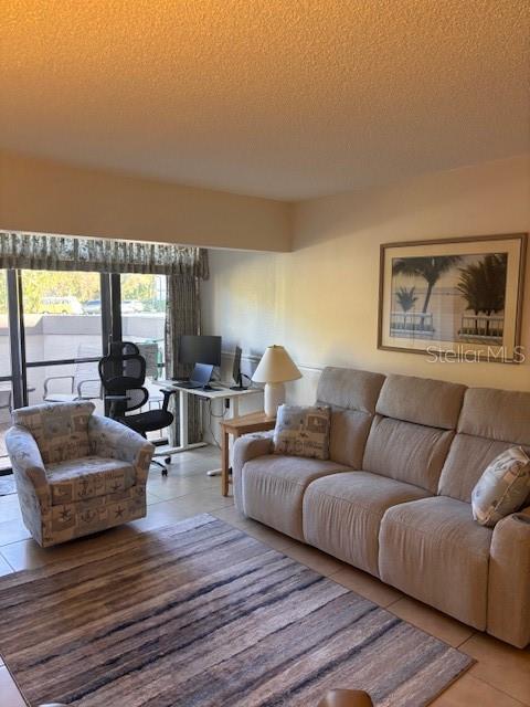 A living room features a beige sofa, patterned armchair, desk area, and a large window — 1515 FORREST NELSON BOULEVARD UNIT L104, PORT CHARLOTTE, FL
