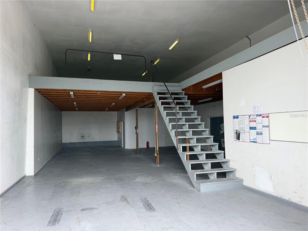 An industrial warehouse space features a concrete floor, a wooden mezzanine, and a metal staircase — 4415 N LOIS AVENUE, TAMPA, FL