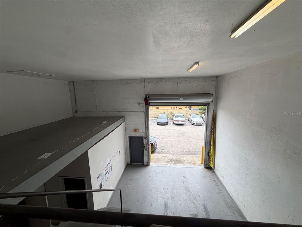 An elevated view of a warehouse interior featuring a mezzanine level and a roll-up door — 4415 N LOIS AVENUE, TAMPA, FL
