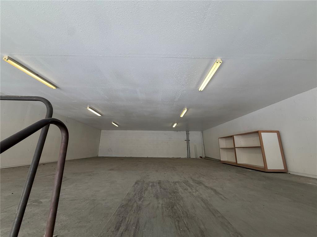 An empty garage features a concrete floor, white walls, and several overhead fluorescent light fixtures — 4415 N LOIS AVENUE, TAMPA, FL