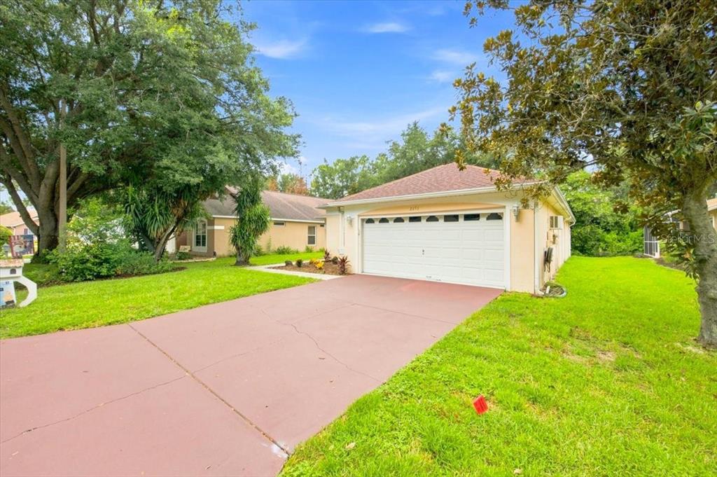 A single-story house with a white garage door and a red concrete driveway — 2393 PAULETTE DRIVE, HAINES CITY, FL