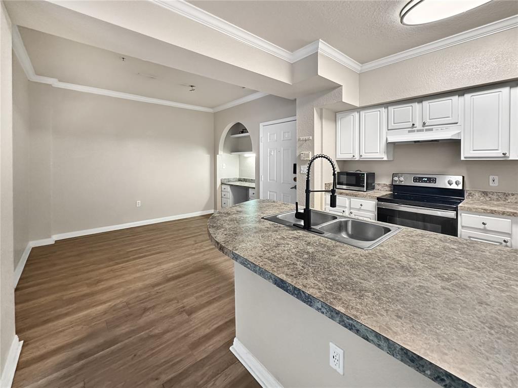 A kitchen with white cabinets, a laminate countertop, and an adjacent dining area — 911 N ORANGE AVENUE UNIT 232, ORLANDO, FL