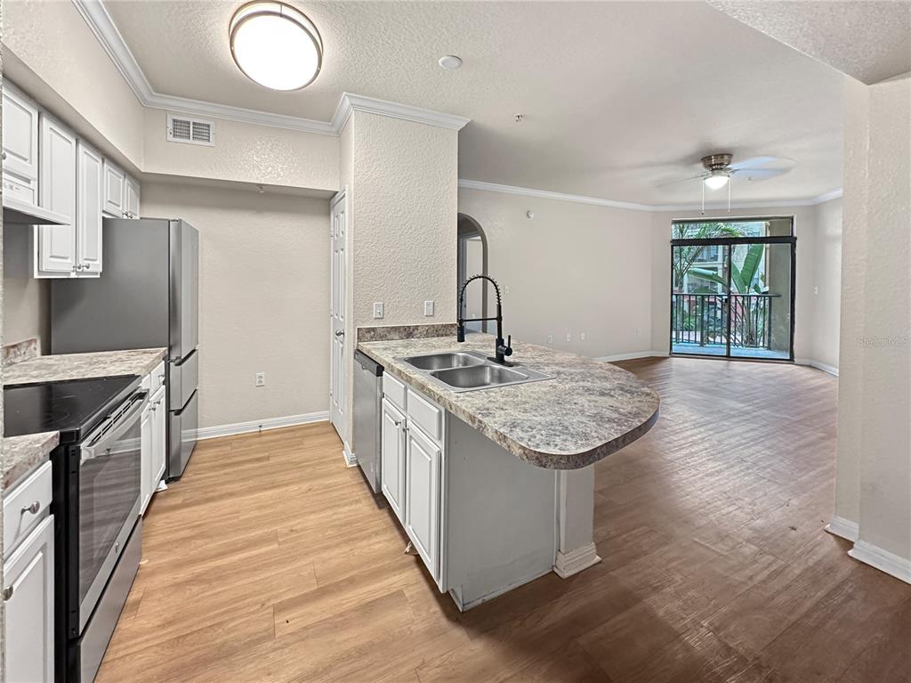 A kitchen with white cabinets and a peninsula overlooks an open living area with balcony access — 911 N ORANGE AVENUE UNIT 232, ORLANDO, FL