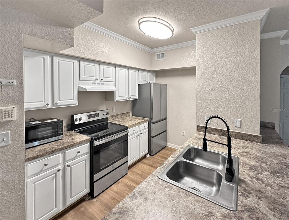 A kitchen features white cabinets, stainless steel appliances, and a double sink with a faucet — 911 N ORANGE AVENUE UNIT 232, ORLANDO, FL