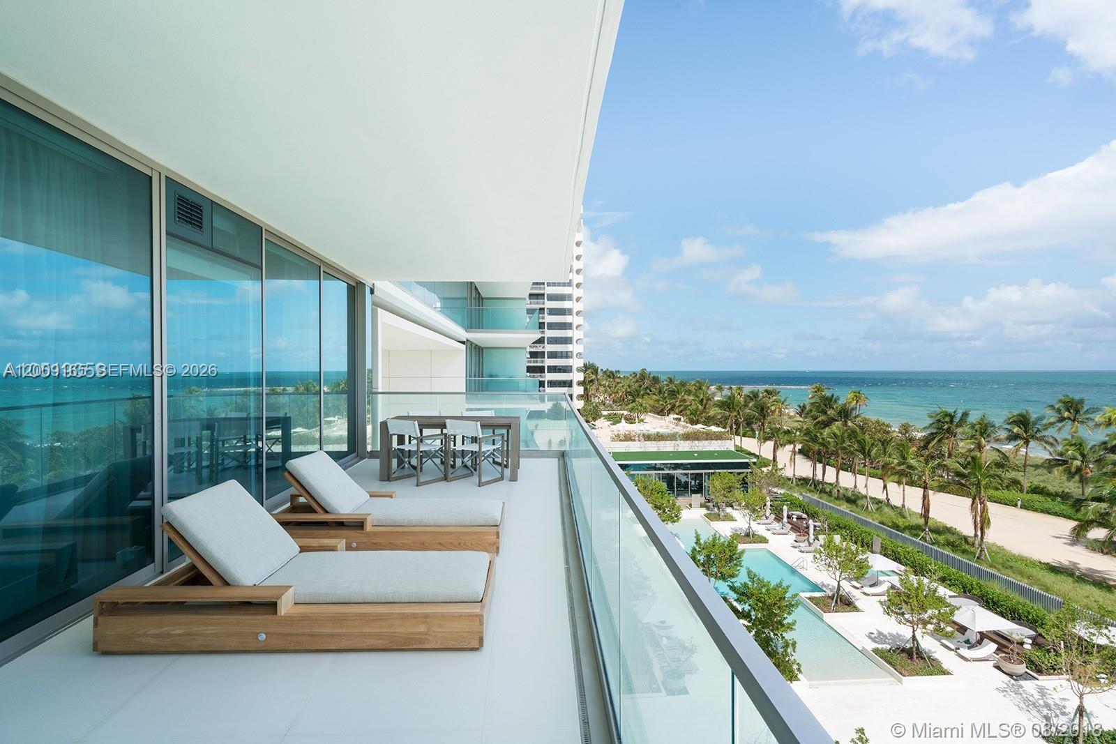 A balcony features two wooden lounge chairs, a dining set, and a glass railing overlooking the ocean — 10201 Collins Ave # 503, Bal Harbour FL 33154, BAL HARBOUR, FL