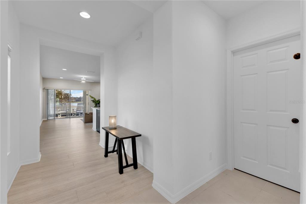 A bright entryway leads to a living area with light wood-look flooring and sliding doors — 4781 MARCOS CIRCLE, KISSIMMEE, FL
