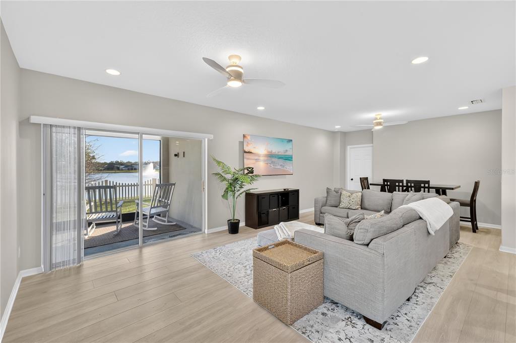 A living room with light wood floors, a gray sectional sofa, and a sliding glass door — 4781 MARCOS CIRCLE, KISSIMMEE, FL