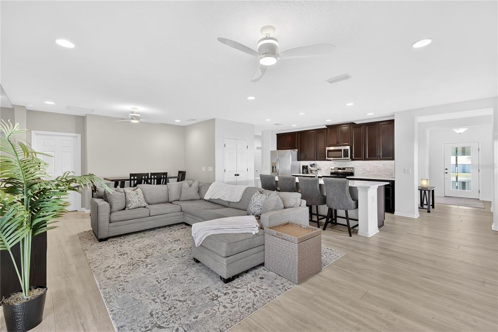 An open-concept living room and kitchen featuring a gray sectional sofa and dark wood cabinets — 4781 MARCOS CIRCLE, KISSIMMEE, FL